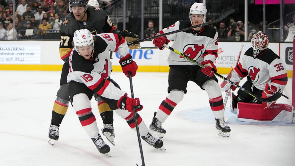 New Jersey Devils center Dawson Mercer (18) gathers the puck against Vegas Golden Knights left wing Max Pacioretty (67) during the second period of an NHL hockey game Monday, April 18, 2022, in Las Vegas. (AP Photo/Joe Buglewicz)