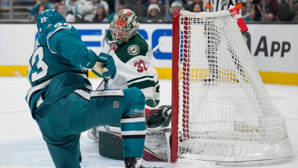 Minnesota Wild goaltender Filip Gustavsson (32) is unable to stop a shot by San Jose Sharks left wing Oskar Lindblom, foreground, for a goal during the second period of an NHL hockey game in San Jose, Calif., Thursday, Dec. 22, 2022. (AP Photo/Godofr