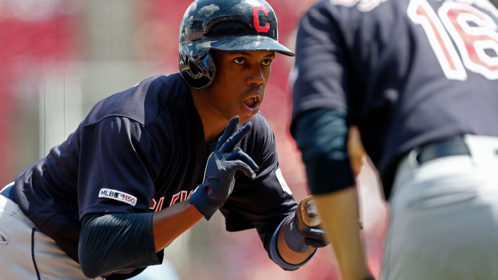 Cleveland Indians' Greg Allen, left, reacts to a triple off Cincinnati Reds relief pitcher Robert Stephenson with third base coach Mike Sarbaugh (16) during the seventh inning of a baseball game, Sunday, July 7, 2019, in Cincinnati. (AP Photo/Gary La