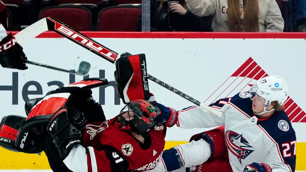 Columbus Blue Jackets defenseman Adam Boqvist (27) collides with Arizona Coyotes goalie Scott Wedgewood (31) during the first period of an NHL hockey game Thursday, Nov. 18, 2021, in Glendale, Ariz. (AP Photo/Ross D. Franklin)