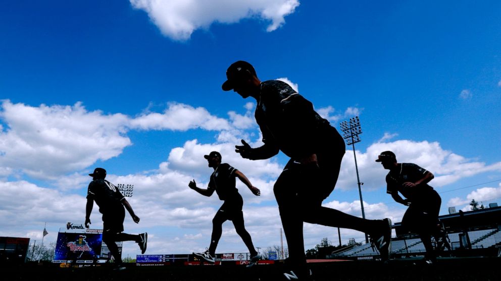 FILE - Quad Cities River Bandits players warm up before a Class-A Midwest League baseball game against the Cedar Rapids Kernels in Cedar Rapids, Iowa, Monday, May 13, 2019. Minor league players and Major League Baseball have reached a settlement in a