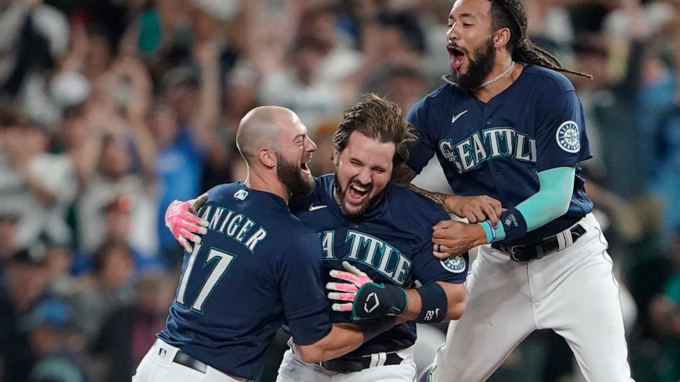 Seattle Mariners' Luis Torrens, center, is greeted by teammates Mitch Haniger, left, and J.P. Crawford, right, after Torrens hit a walk-off RBI single to give the Mariners a 1-0 win over the New York Yankees in a 13-inning baseball game, Tuesday, Aug