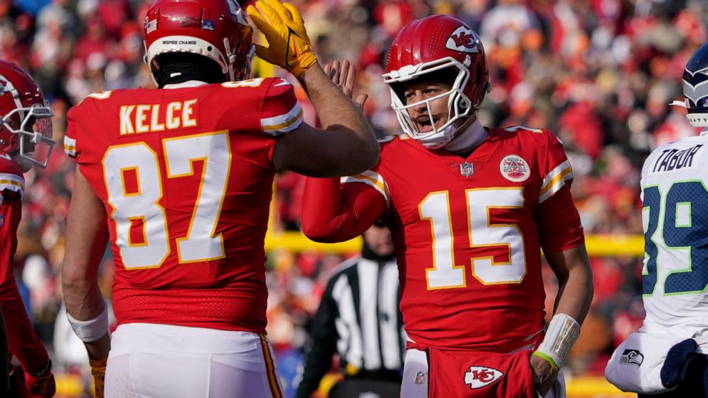 Kansas City Chiefs quarterback Patrick Mahomes (15) and tight end Travis Kelce (87) celebrate during the first half of an NFL football game against the Seattle Seahawks Saturday, Dec. 24, 2022, in Kansas City, Mo. (AP Photo/Ed Zurga)