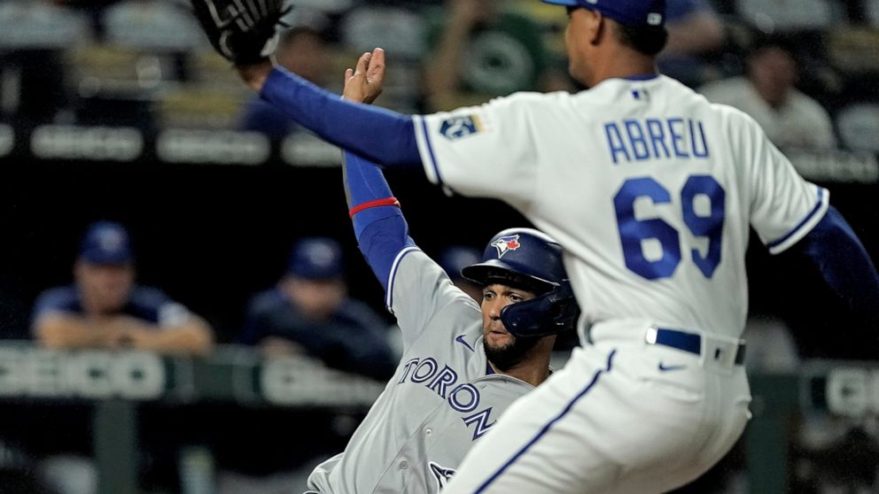 Toronto Blue Jays' Lourdes Gurriel Jr. beats the tag by Kansas City Royals relief pitcher Albert Abreu (69) to score on a wild pitch during the eighth inning of a baseball game Monday, June 6, 2022, in Kansas City, Mo. (AP Photo/Charlie Riedel)