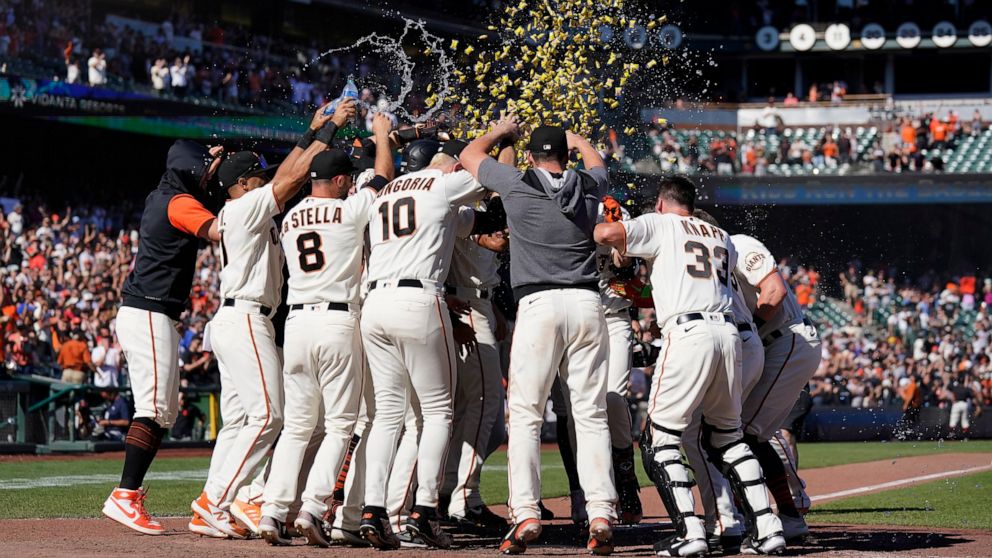 San Francisco Giants players celebrate after Wilmer Flores, hidden, hit a two-run home run during the ninth inning of a baseball game against the Philadelphia Phillies in San Francisco, Sunday, Sept. 4, 2022. (AP Photo/Jeff Chiu)