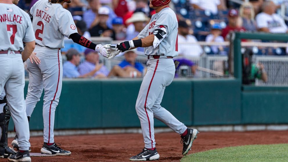 Arkansas' Chris Lanzilli (18) gets five from Jalen Battles (2) after his home run in the second inning against Mississippi during an NCAA College World Series baseball game Wednesday, June 22, 2022, in Omaha, Neb. (AP Photo/John Peterson)