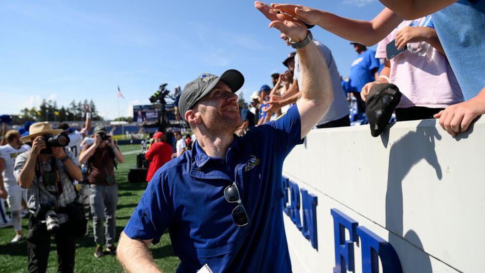 Delaware head coach Ryan Carty high fives fans after an NCAA college football game against Navy, Saturday, Sept. 3, 2022, in Annapolis, Md. Delaware won 14-7. (AP Photo/Nick Wass)