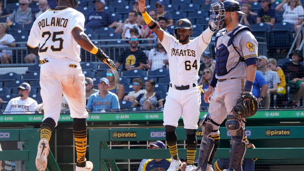 Pittsburgh Pirates' Rodolfo Castro (64) celebrates as Gregory Polanco (25) comes in to score in front of Milwaukee Brewers catcher Manny Pina on a double by Kevin Newman in the fifth inning of the first game of a split doubleheader baseball game, Sat