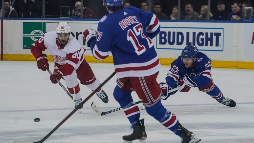 Detroit Red Wings center Joe Veleno (90) goes after loose puck against New York Rangers center Kevin Rooney (17) and New York Rangers defenseman Adam Fox (23) during second period of NHL hockey game, Saturday April 16, 2022, in New York. (AP Photo/Be