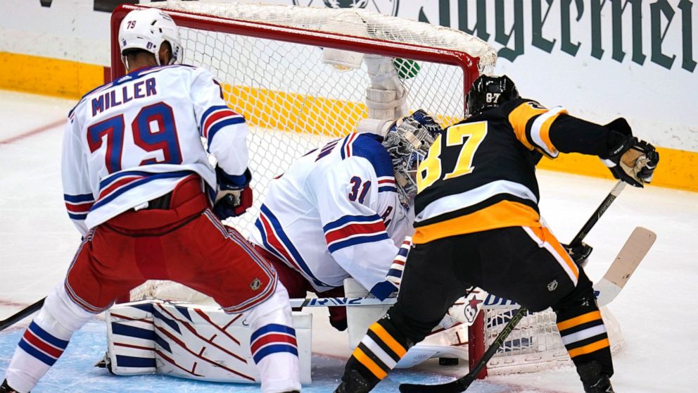 Pittsburgh Penguins' Sidney Crosby (87) pokes the puck under the pad of New York Rangers goaltender Igor Shesterkin (31) for a goal with K'Andre Miller (79) defending during the first period in Game 4 of an NHL hockey Stanley Cup first-round playoff 