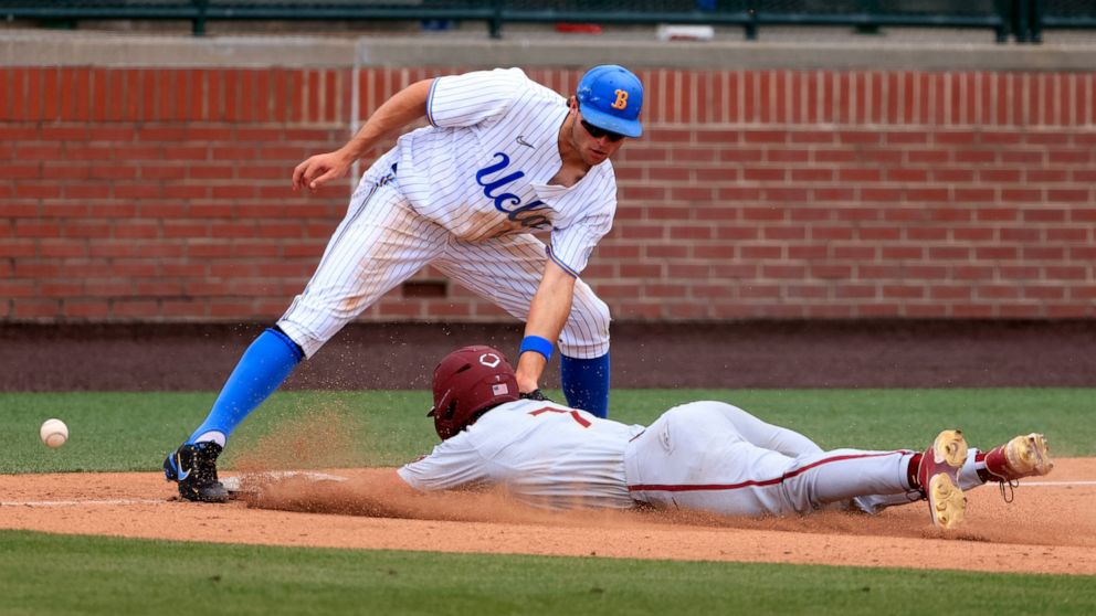 UCLA infielder Kyle Karros (44) mishandles the ball as Florida State's Jaime Ferrer (7) slides safely into third base during an NCAA baseball game on Friday, June 3, 2022, in Auburn, Ala. (AP Photo/Butch Dill)