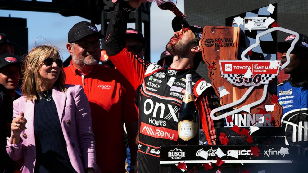 El mexicano Daniel Suárez festeja su victoria bebiendo vivo en la NASCAR Cup Series en Sonoma, California, el domingo 12 de junio de 2022. (AP Foto/D. Ross Cameron)