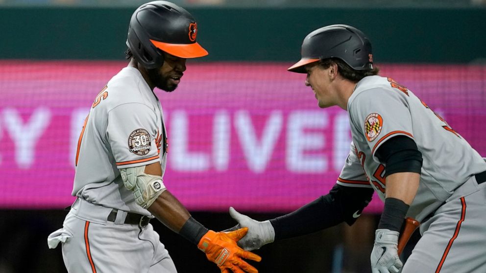 Baltimore Orioles' Cedric Mullins, left, and Adley Rutschman, right, celebrate after Mullins hit a lead-off home run in the first inning of a baseball game against the Texas Rangers, Monday, Aug. 1, 2022, in Arlington, Texas. (AP Photo/Tony Gutierrez)