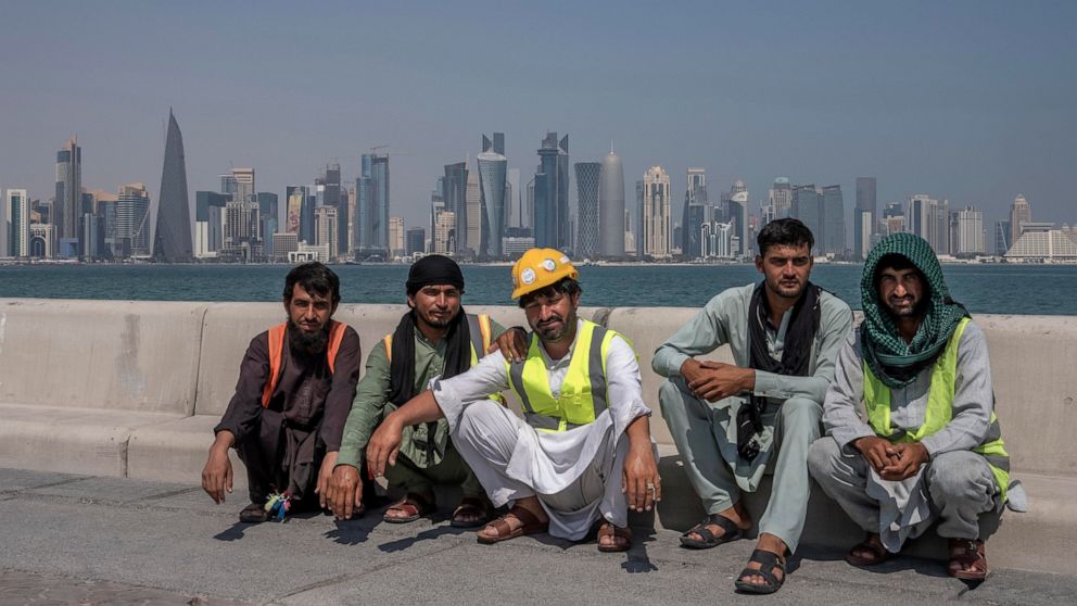 FILE - Pakistani migrant laborers pose for a photograph, as they take a break, on the corniche, overlooking the skyline of Doha, Qatar, Wednesday, Oct. 19, 2022. Migrant laborers who built Qatar's World Cup stadiums often worked long hours under hars