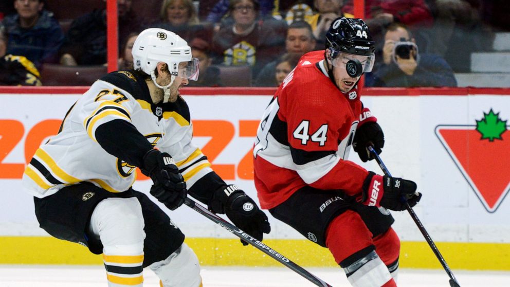 The puck floats in the face of Ottawa Senators' Jean-Gabriel Pageau as Boston Bruins' John Moore puts the pressure on during second period NHL action in Ottawa, Monday, Dec. 9, 2019. (Sean Kilpatrick/The Canadian Press via AP)