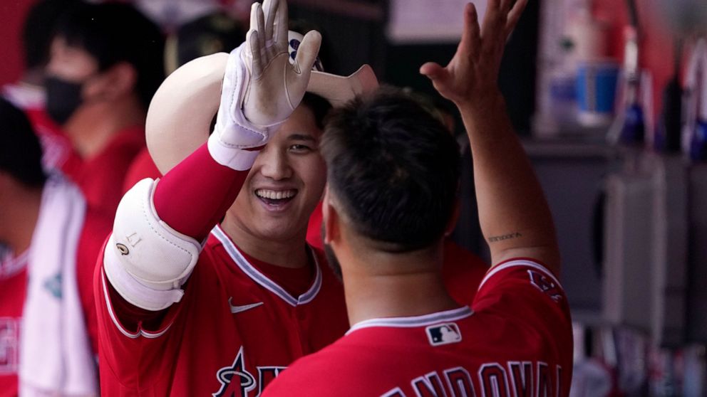 Los Angeles Angels' Shohei Ohtani, left, celebrates in the dugout with starting pitcher Patrick Sandoval after hitting a solo home run during the first inning of a baseball game against the Oakland Athletics Sunday, May 22, 2022, in Anaheim, Calif. (