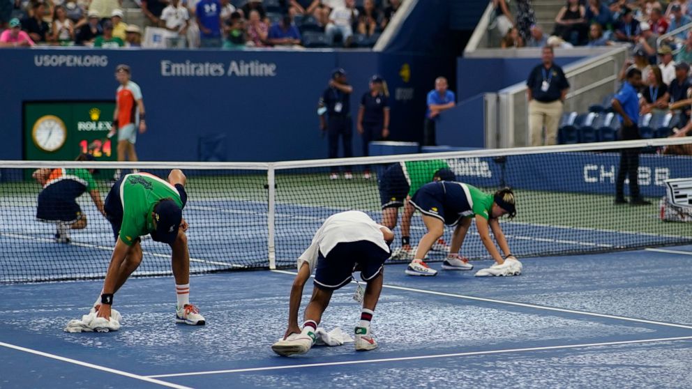 Court workers dry the surface after rain stopped play between Andrey Rublev, of Russia, and Cameron Norrie, of Great Britain, during the fourth round of the U.S. Open tennis championships, Monday, Sept. 5, 2022, in New York. (AP Photo/Eduardo Munoz A