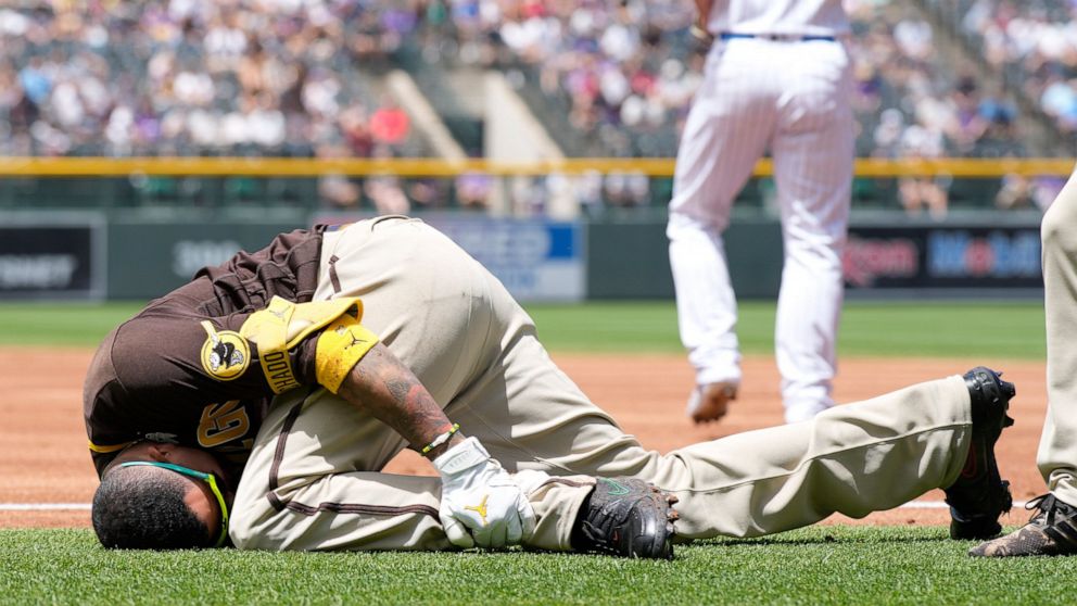 San Diego Padres' Manny Machado grabs his left ankle after being injured while trying to run out a ground ball hit to Colorado Rockies starting pitcher Antonio Senzatela in the first inning of a baseball game, Sunday, June 19, 2022, in Denver. Machad