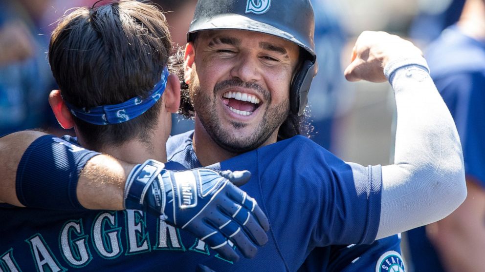 Seattle Mariners' Eugenio Suarez, right, hugs Sam Haggerty in the dugout to celebrate Suarez's two-run home run against the Los Angeles Angels during the fifth inning of a baseball game in Anaheim, Calif., Wednesday, Aug. 17, 2022. (AP Photo/Alex Gal