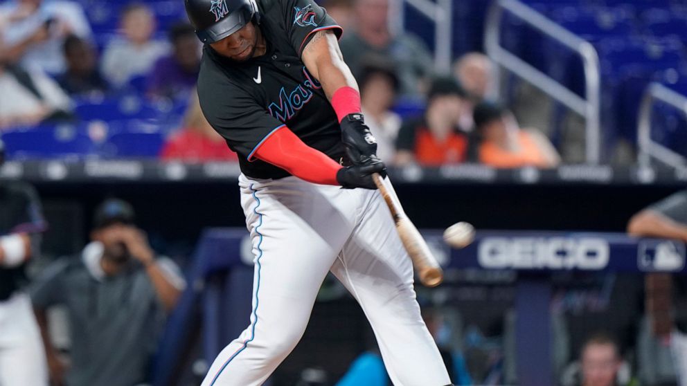 Miami Marlins' Jesus Aguilar hits a home run scoring Miguel Rojas, during the fourth inning of the first game of a baseball doubleheader against the Atlanta Braves, Saturday, Aug. 13, 2022, in Miami. (AP Photo/Wilfredo Lee)