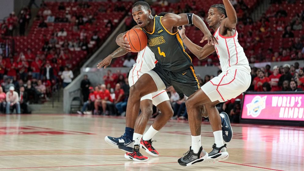 North Carolina A&T forward Marcus Watson (4) bursts through a double-team by Houston guards Tramon Mark (12) and Jamal Shead (rear) during the first half of an NCAA college basketball game, Tuesday, Dec. 13, 2022, in Houston. (AP Photo/Kevin M. Cox)