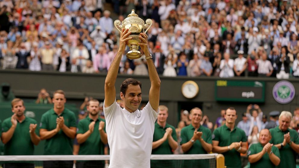 FILE - Switzerland's Roger Federer is applauded by ground staff as he holds the trophy after defeating Croatia's Marin Cilic to win the Men's Singles final match on day thirteen at the Wimbledon Tennis Championships in London Sunday, July 16, 2017. F