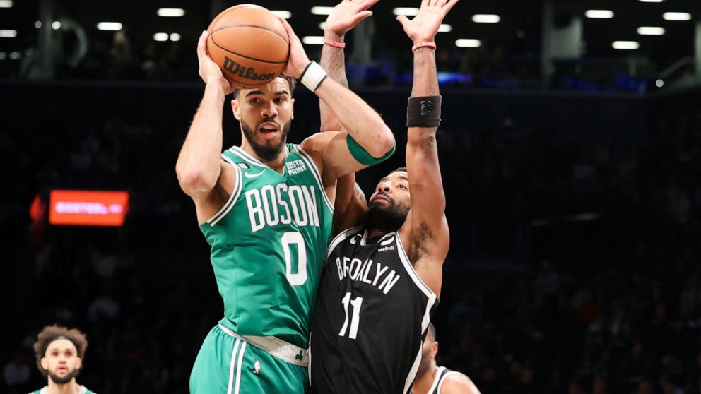 Boston Celtics forward Jayson Tatum (0) looks to pass the ball against Brooklyn Nets guard Kyrie Irving (11) during the first half of an NBA basketball game, Sunday, Dec. 4, 2022, in New York. (AP Photo/Jessie Alcheh)