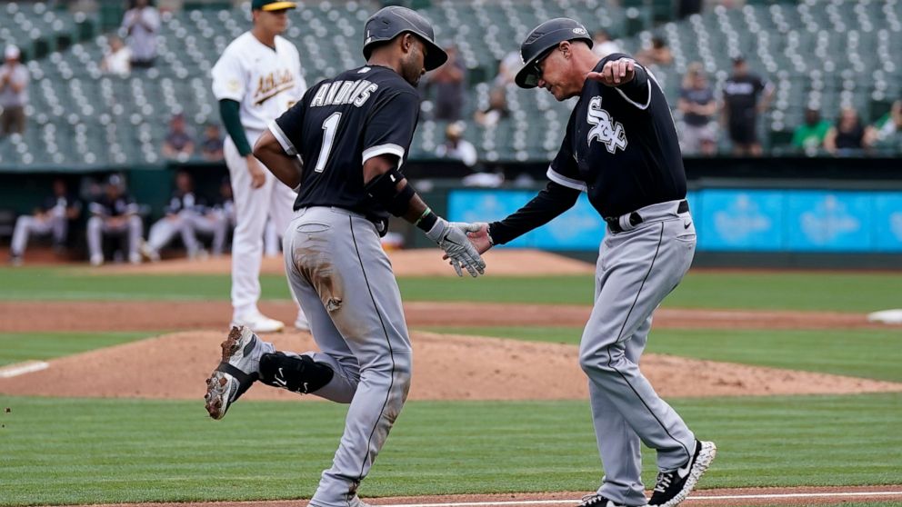 Chicago White Sox's Elvis Andrus (1) is congratulated by third base coach Joe McEwing after hitting a three-run home run off of Oakland Athletics pitcher Adrian Martinez, rear, during the second inning of a baseball game in Oakland, Calif., Saturday,