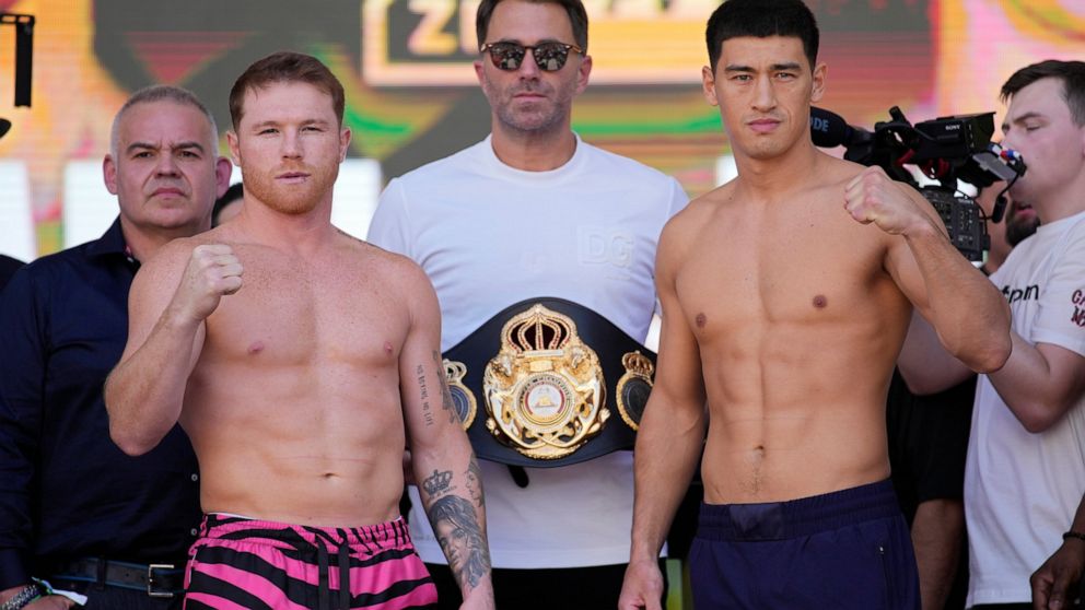 Canelo Alvarez, left, and Dmitry Bivol, right, pose next to promoter Eddie Hearn during a ceremonial weigh-in for their Saturday boxing fight, Friday, May 6, 2022, in Las Vegas. (AP Photo/John Locher)