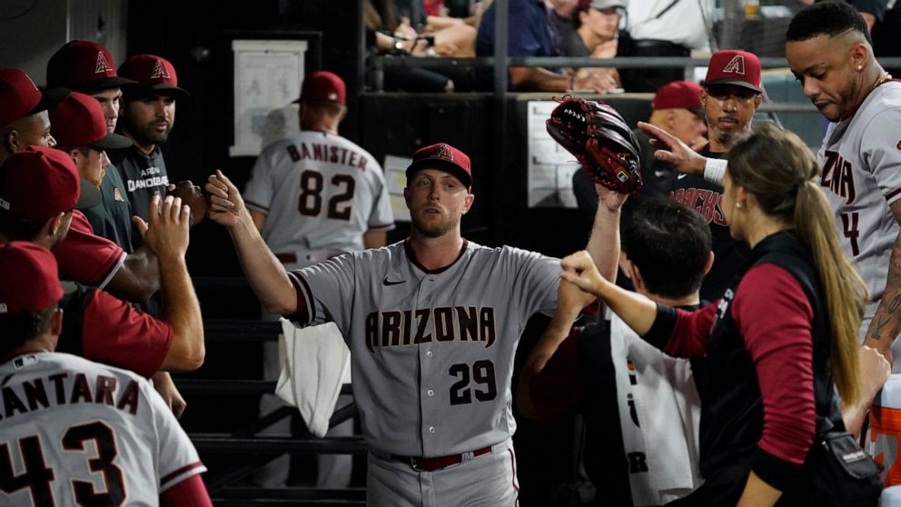 Arizona Diamondbacks starting pitcher Merrill Kelly (29) is greeted in the dugout after leaving a baseball game against the Chicago White Sox during the eighth inning Saturday, Aug. 27, 2022, in Chicago. (AP Photo/David Banks)