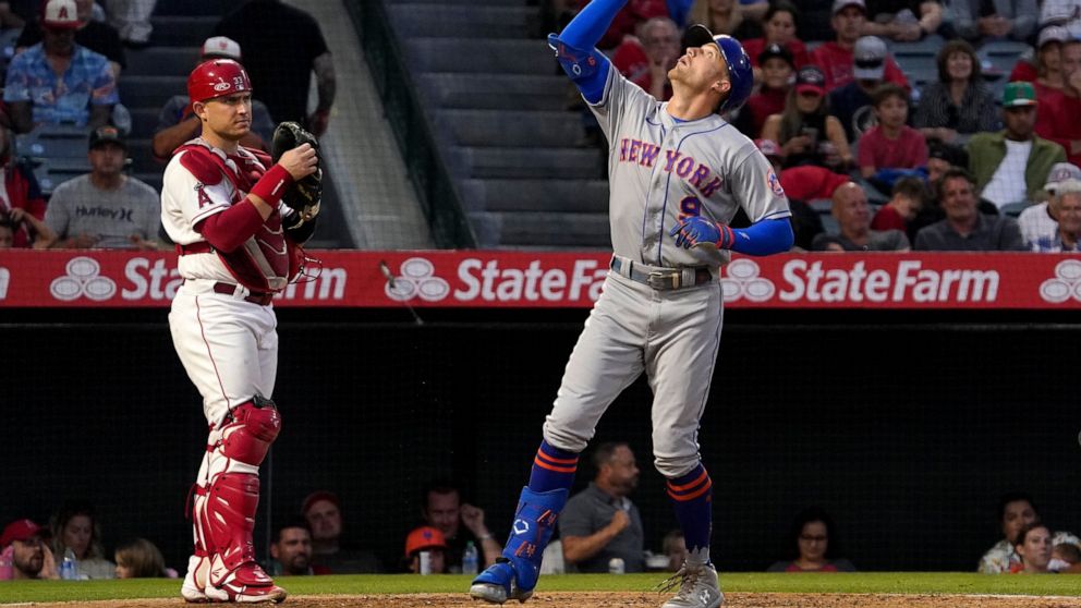 New York Mets' Brandon Nimmo, right, gestures as he scores after hitting a solo home run as Los Angeles Angels catcher Max Stassi stands at the plate during the fourth inning of a baseball game Friday, June 10, 2022, in Anaheim, Calif. (AP Photo/Mark