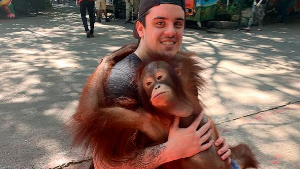 This photo provided by Tom Straschnitzki shows Ryan Straschnitzki as he plays with an orangutan during a visit to the Safari World zoo in Bangkok, Thailand, Sunday, Dec. 1, 2019. Ryan was left paralyzed from the chest down after the bus carrying his 