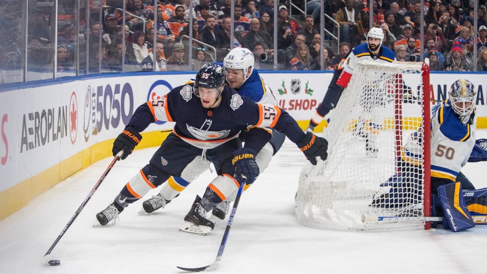 St. Louis Blues' Colton Parayko (55) and Edmonton Oilers' Dylan Holloway (55) fight for the puck behind Blues goalie Jordan Binnington (50) during the second period of an NHL hockey game, Thursday, Dec. 15, 2022 in Edmonton Alberta. (Amber Bracken/Th