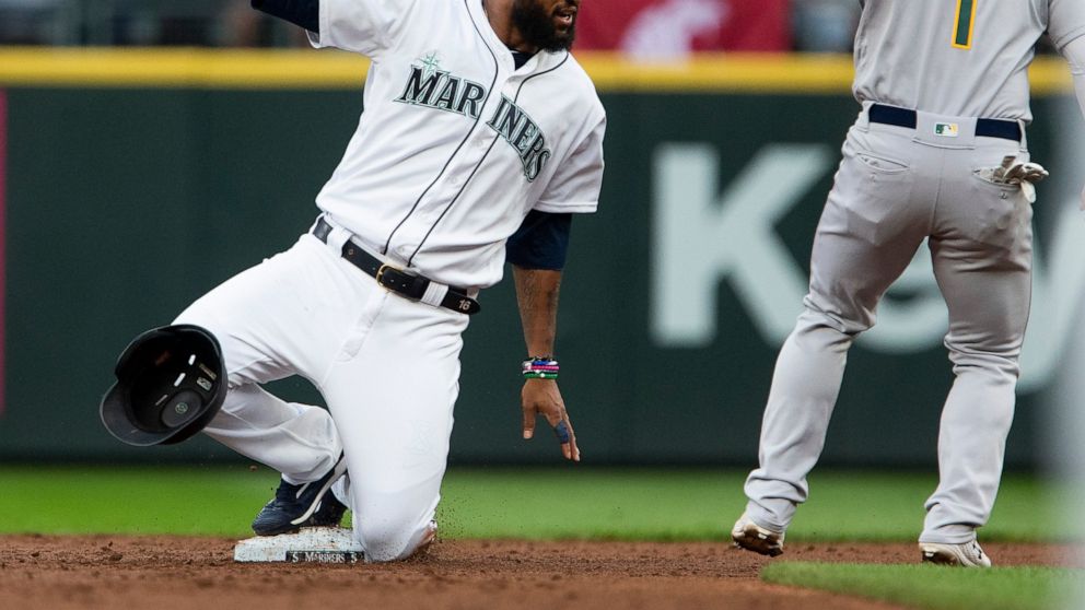 Seattle Mariners' Domingo Santana loses his helmet as he steals second base ahead of the tag by Oakland Athletics second baseman Franklin Barreto (1) during the first inning of a baseball game Saturday, July 6, 2019, in Seattle. (AP Photo/Lindsey Wasson)