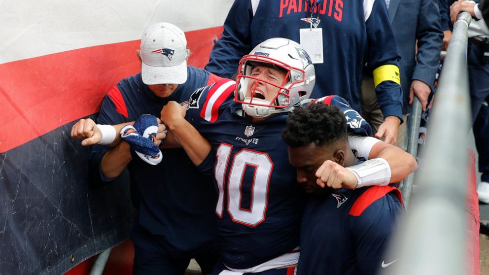 New England Patriots quarterback Mac Jones (10) is helped off the field after suffering a leg injury with less than two minutes to play in the second half of an NFL football game against the Baltimore Ravens, Sunday, Sept. 25, 2022, in Foxborough, Ma