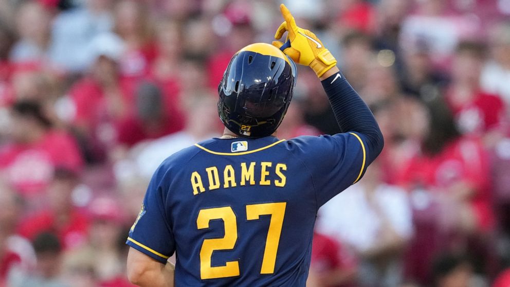 Milwaukee Brewers' Willy Adames (27) scores after hitting a solo home run during the fifth inning of the team's baseball game against the Cincinnati Reds, Friday, June 17, 2022, in Cincinnati. (AP Photo/Jeff Dean)