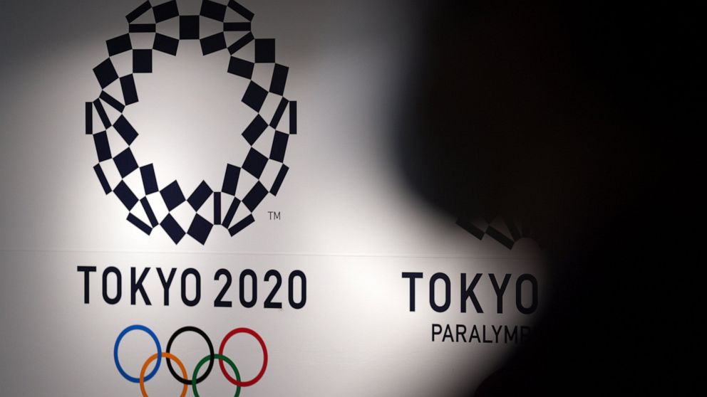 FILE - A person walks near Tokyo 2020 logo in Haneda Airport on June 14, 2021, in Tokyo. Tokyo Olympic officials, meeting Tuesday, June 21, 2022, before the body is dissolved at the end of the month, were to detail the final numbers that were driven 