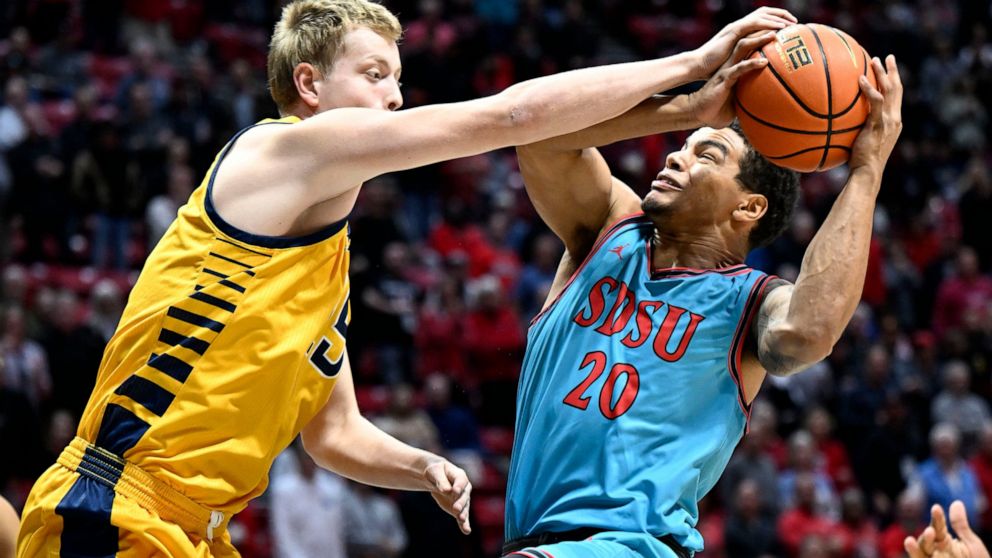 San Diego State guard Matt Bradley (20) is fouled by UC Irvine center Bent Leuchten (15) during the first half of an NCAA college basketball game Tuesday, Nov. 29, 2022, in San Diego. (AP Photo/Denis Poroy)