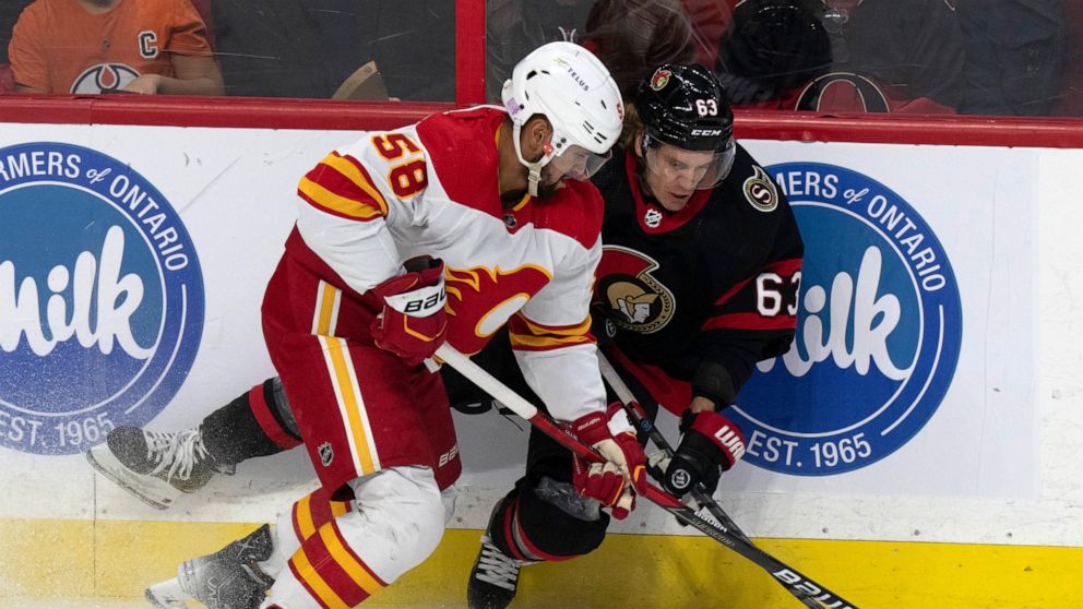 Calgary Flames defenseman Oliver Kylington (58) knocks Ottawa Senators right wing Tyler Ennis off the puck during the first period of an NHL hockey game, in Ottawa, Ontario, Sunday, Nov. 14, 2021. (Adrian Wyld/The Canadian Press via AP)
