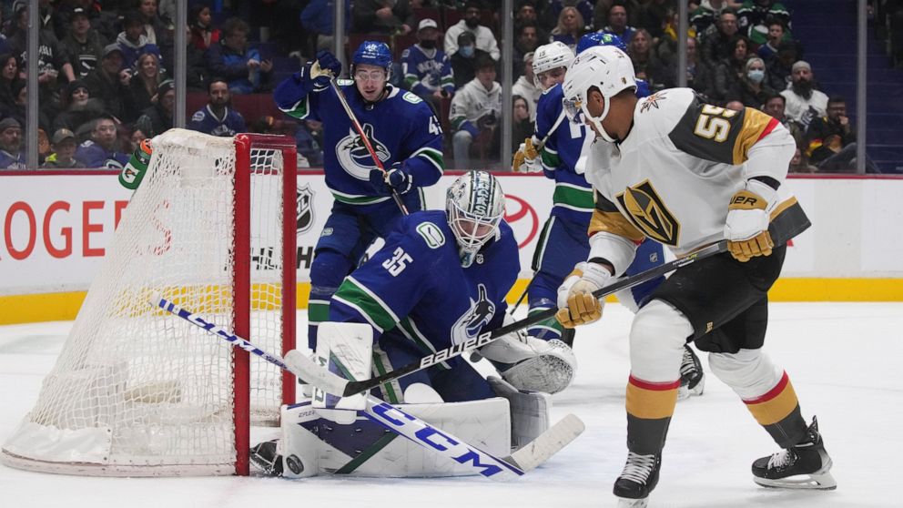 Vancouver Canucks goalie Thatcher Demko, left, stops Vegas Golden Knights' Keegan Kolesar during the second period of an NHL hockey game Tuesday, April 12, 2022, in Vancouver, British Columbia. (Darryl Dyck/The Canadian Press via AP)