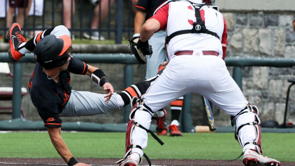 Virginia Tech's Jack Hurley (31) flips after being tagged by Oklahoma catcher Jimmy Crooks (3) in the fifth inning of an NCAA college baseball tournament super regional game Saturday, June 11, 2022, Blacksburg, Va. (AP Photo/Matt Gentry)