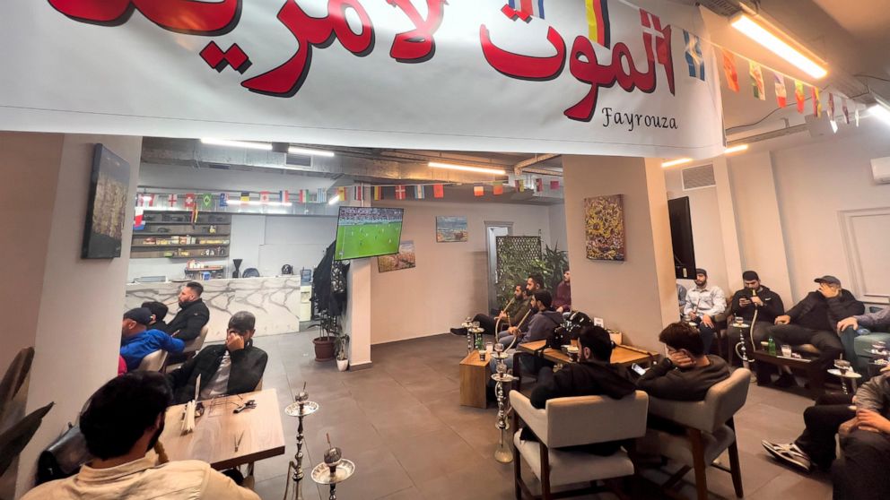 Lebanese fans of Iran's team, sit at a coffee shop under an Arabic banner that reads: "Death to America" as they watch the World Cup group B soccer match between Iran and the United States, in the Hezbollah stronghold in the southern suburbs of Beiru