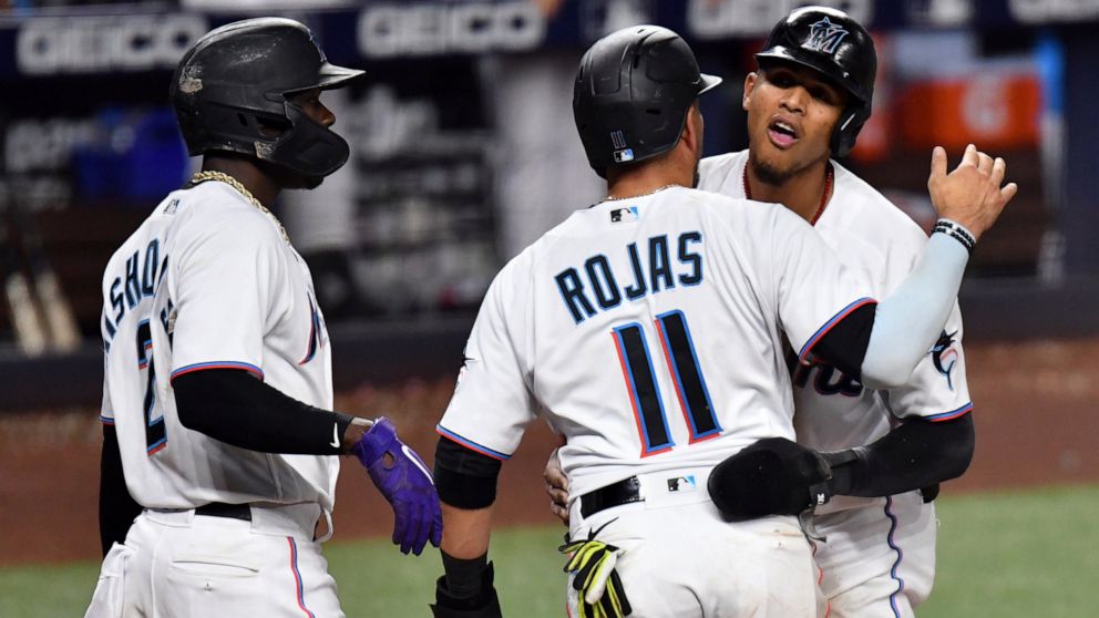 Miami Marlins' Erik Gonzalez, right, and Miguel Rojas (11) celebrate scoring runs during the seventh inning of a baseball game against the Washington Nationals as teammate Jazz Chisholm Jr. (2) looks on, Tuesday, May 17, 2022, in Miami. (AP Photo/Jim