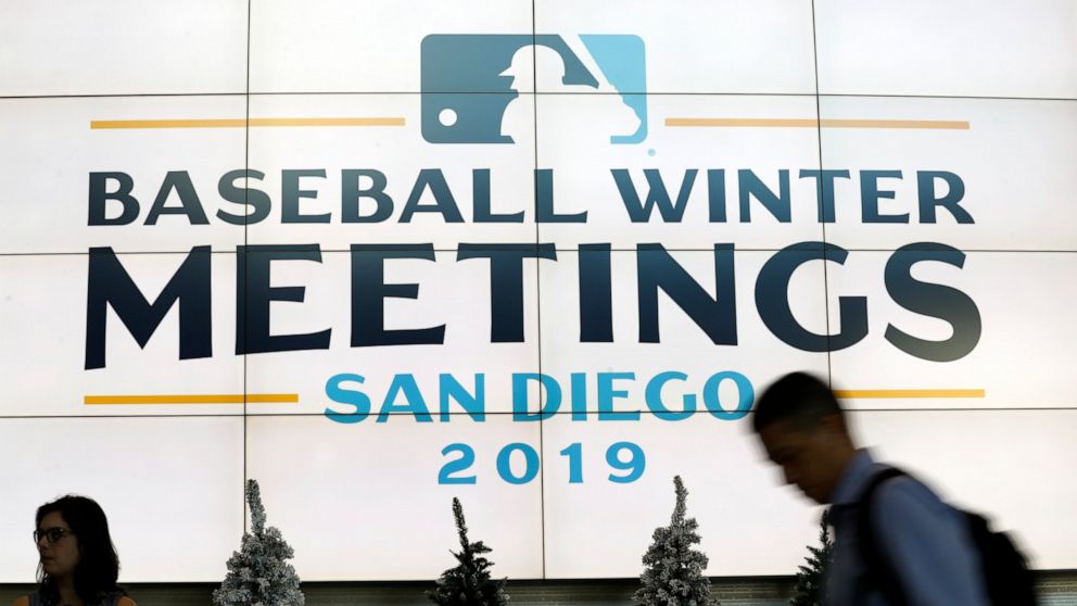 People pass a display during the Major League Baseball winter meetings Monday, Dec. 9, 2019, in San Diego. (AP Photo/Gregory Bull)