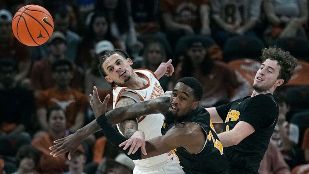 Texas forward Christian Bishop, left, and Arkansas-Pine Bluff guard Shaun Doss Jr., center, battle for a loose ball during the first half of an NCAA college basketball game in Austin, Texas, Saturday, Dec. 10, 2022. (AP Photo/Eric Gay)