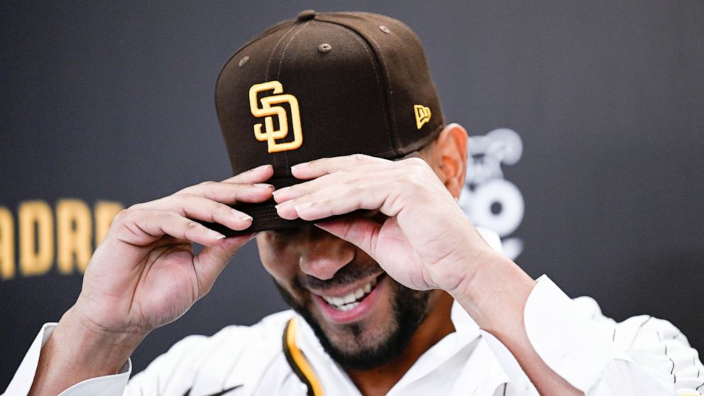 San Diego Padres' Xander Bogaerts puts on a Padres cap at a news conference held to announce that his $280 million, 11-year contact with the Padres has been finalized, Friday, Dec. 9, 2022, in San Diego. (AP Photo/Denis Poroy)