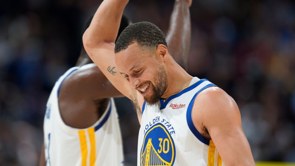 Golden State Warriors guard Stephen Curry, front, congratulates forward Draymond Green near the endoof Game 3 of the team's NBA basketball first-round Western Conference playoff series against the Denver Nuggets Thursday, April 21, 2022, in Denver. (