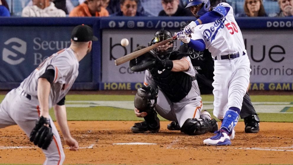 Los Angeles Dodgers right fielder Mookie Betts, right, hits a solo home run as San Francisco Giants starting pitcher Alex Wood, left, and catcher Joey Bart watch during the sixth inning of a baseball game Wednesday, May 4, 2022, in Los Angeles. (AP P