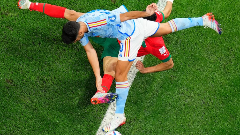 Spain's Marco Asensio, top, and Morocco's Nayef Aguerd challenge for the ball during the World Cup round of 16 soccer match between Morocco and Spain, at the Education City Stadium in Al Rayyan, Qatar, Tuesday, Dec. 6, 2022. (AP Photo/Petr David Josek)