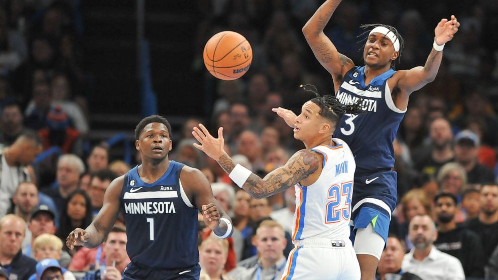Oklahoma City Thunder guard Tre Mann (23) tries to keep the ball away from Minnesota Timberwolves forwards Anthony Edwards (1) and Jaden McDaniels (3) in the second half of an NBA basketball game, Sunday, Oct. 23, 2022, in Oklahoma City. (AP Photo/Ky